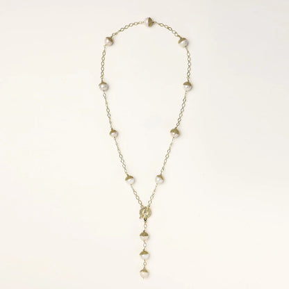 Gold-plated lariat necklace with baroque pearls and textured caps on cream background, showing adjustable Y-shaped design.