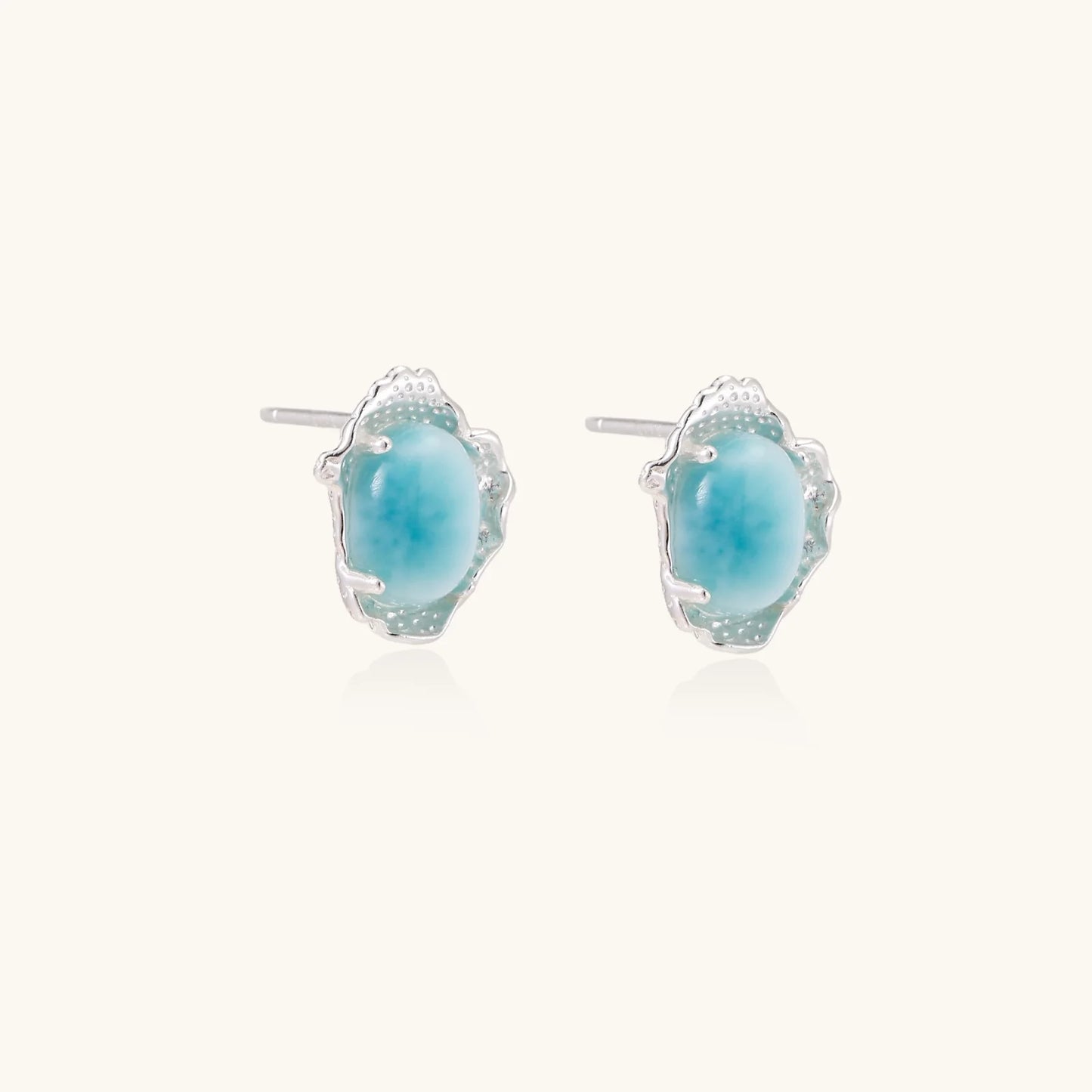Oval larimar gemstone studs with ornate silver settings showing natural turquoise marbling on cream background