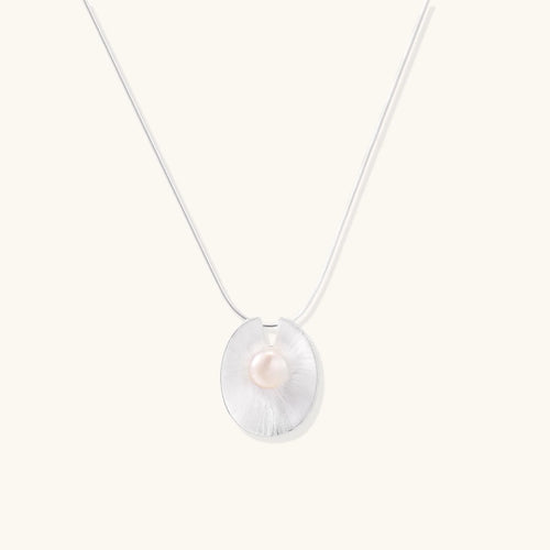 Sterling silver disc necklace with textured finish and centered freshwater pearl on delicate chain
