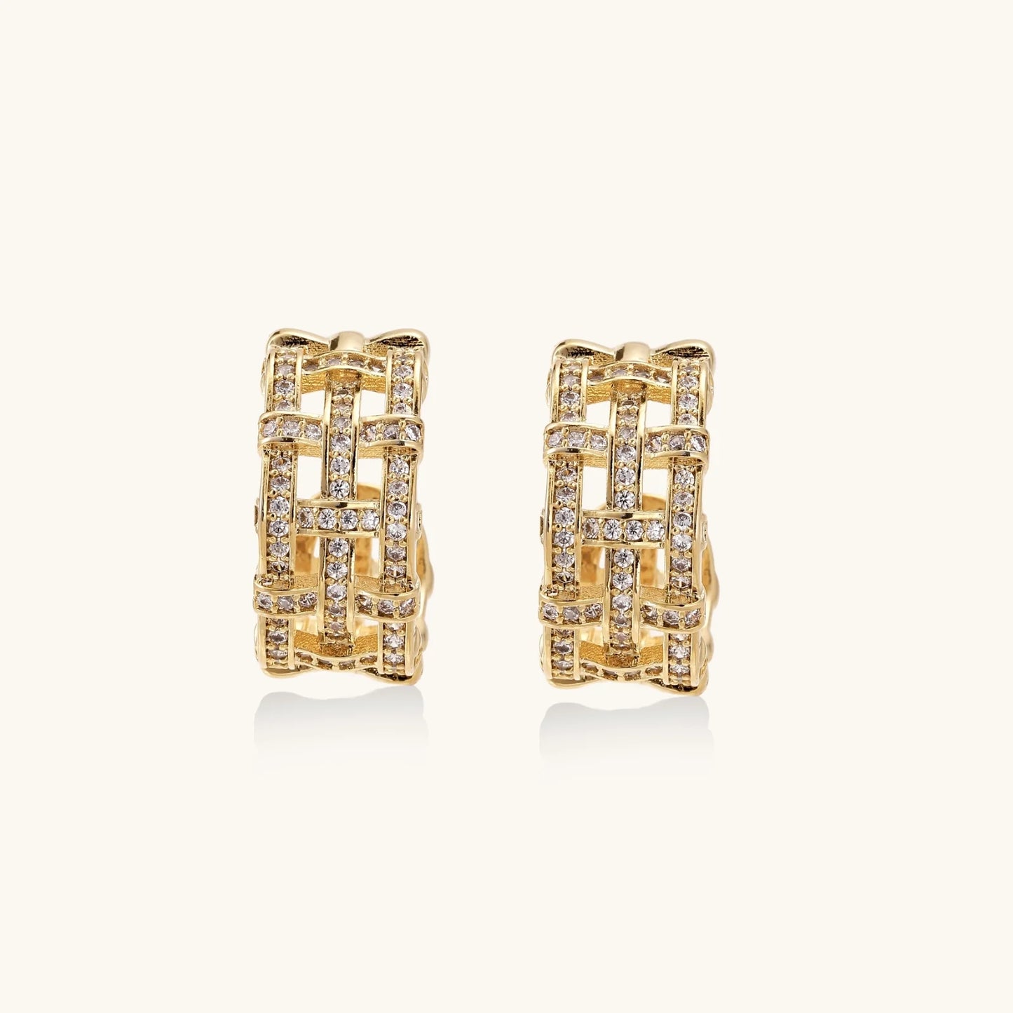 Gold-plated geometric hoop earrings with basket-weave lattice design and pavé crystal accents on cream background