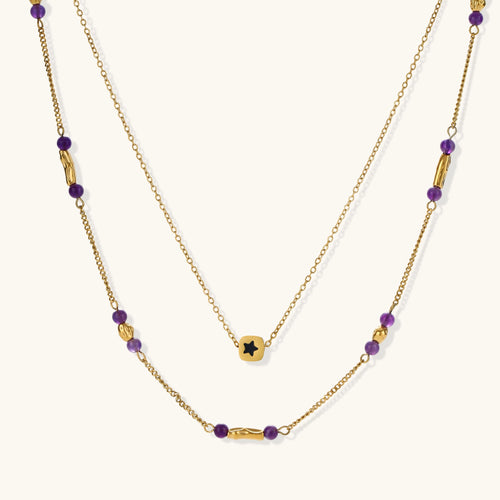 Two layered gold-tone necklaces with purple stone beads and star pendant against cream background.